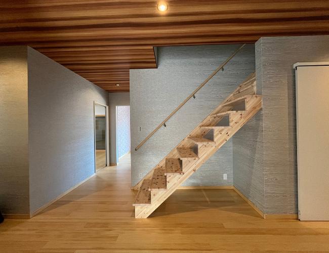 玄関前には、桧の無垢できた階段がお出迎え。 グレーの壁紙がモダンな印象になっています。